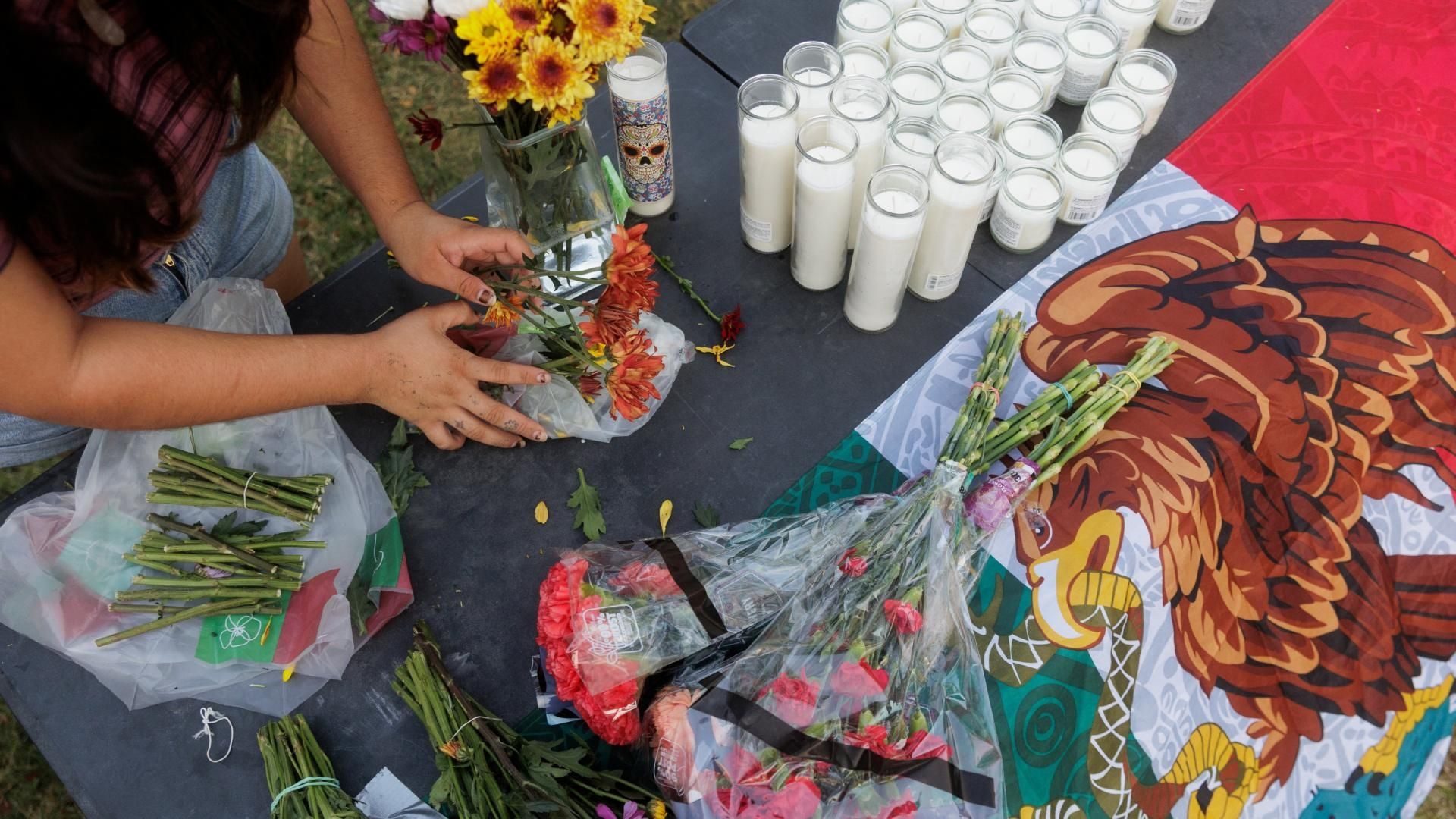 una bandera de México rodeada de flores y veladoras por mexicano que recibió disparos en sede de ICE, en Dallas