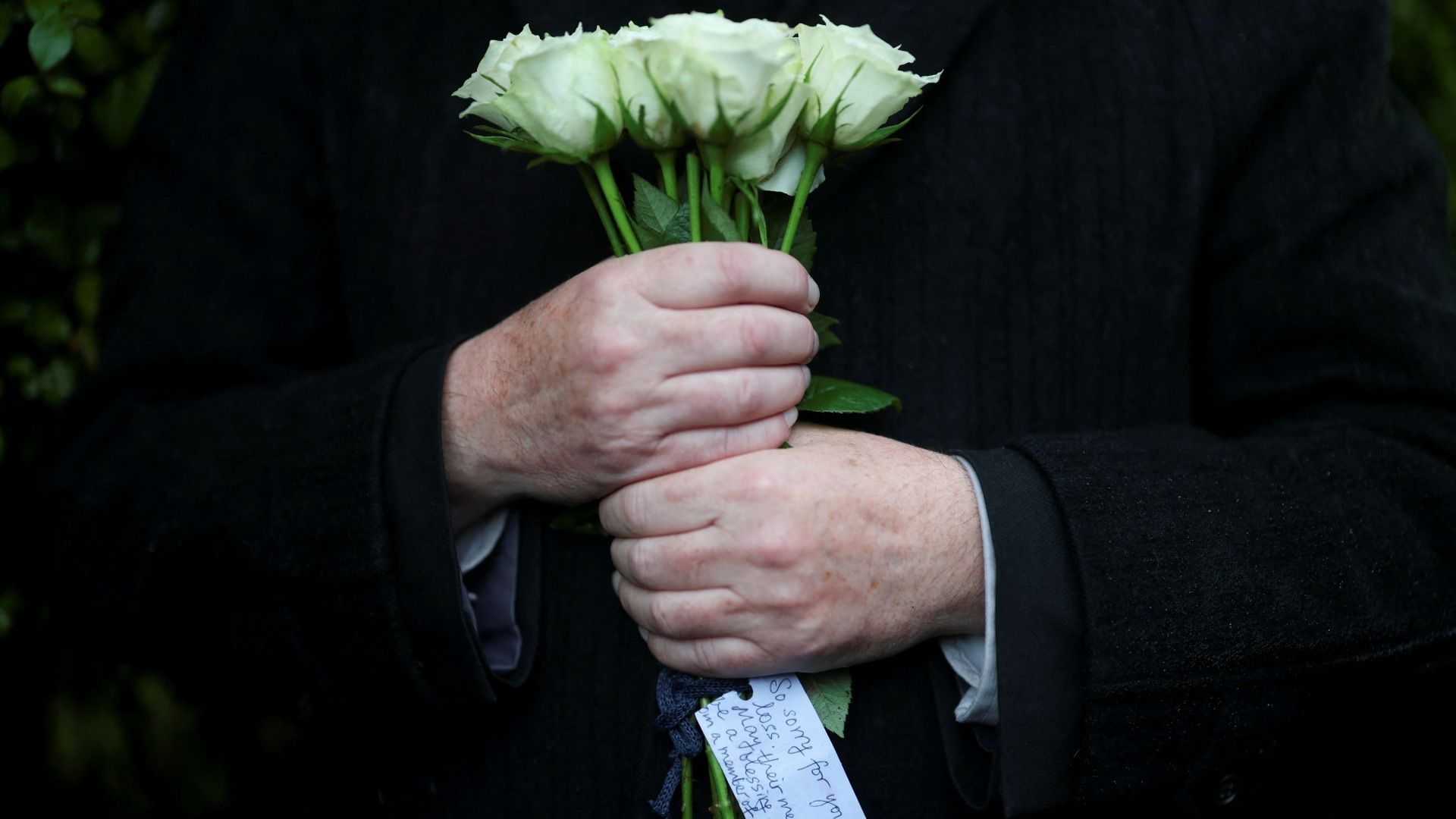 Mujer sostiene un ramo de flores blancas en señal de luto por el atentado terrorista en Manchester